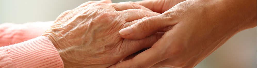 Close-up of an elderly hand being held by a younger hand, symbolizing care and support.