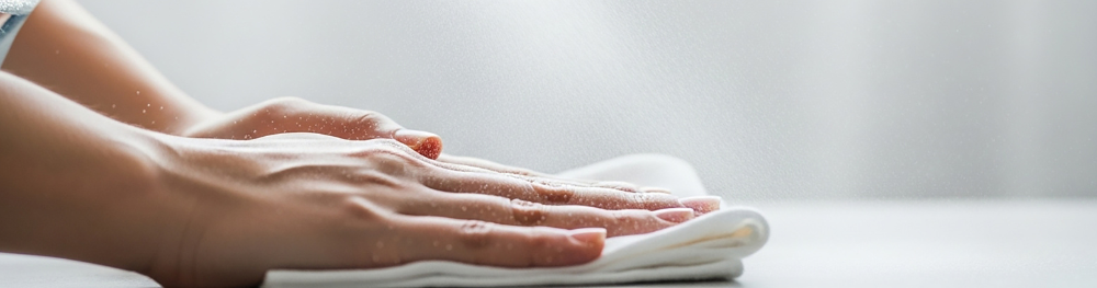 Person holding a stack of white towels with a blurred background